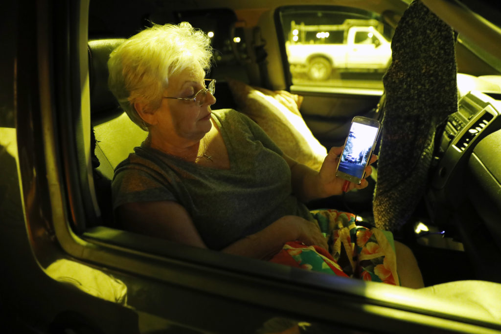 Volcano evacuee Stella Calio, a resident of Leilani Estates, watches social media videos of the volcanic eruption that took place just blocks from her home, Friday, May 4, 2018, in Pahoa, HI. Calio, her husband, and two dogs are staying at a shelter a few miles from the lava eruption. (AP Photo/Marco Garcia)