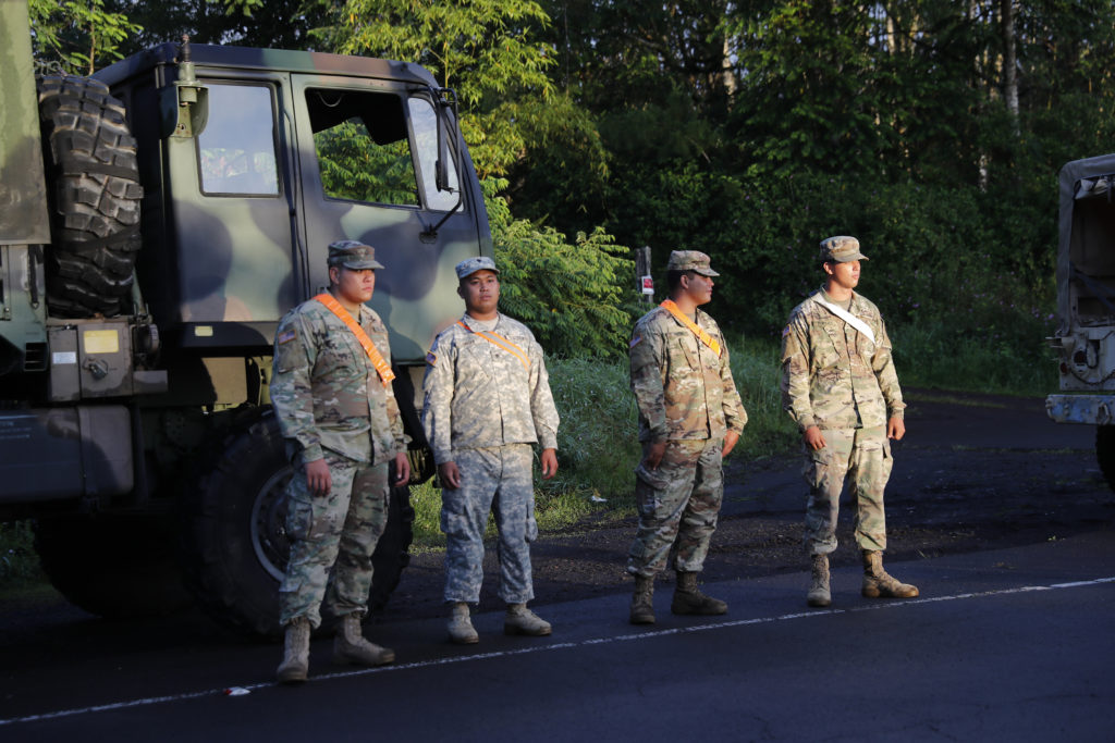 National guardsmen across from the entrance to Leilani Estates, Friday, May 4, 2018, in Pahoa, HI. A mandatory evacuation for the area as declared by the state. Due to unsafe conditions in the area from the recent lava eruption, residents who evacuated could not return to their homes Friday. (AP Photo/Marco Garcia)